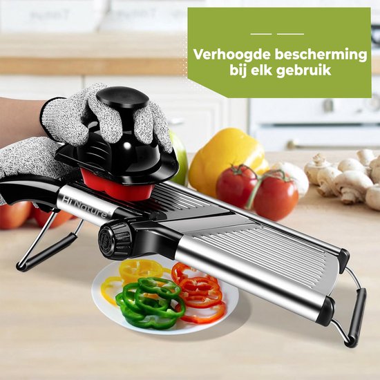 Hand met snijhandschoen gebruikt mandoline om tomaat te snijden. Plateau met gesneden paprika's.