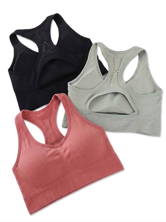 Drie naadloze sportbeha's in zwart, groen en roze met racerback en open rug design.