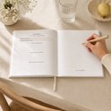 Open zwangerschapsdagboek met schrijfruimte. Een hand schrijft met een pen. Maand 6 van de zwangerschap.