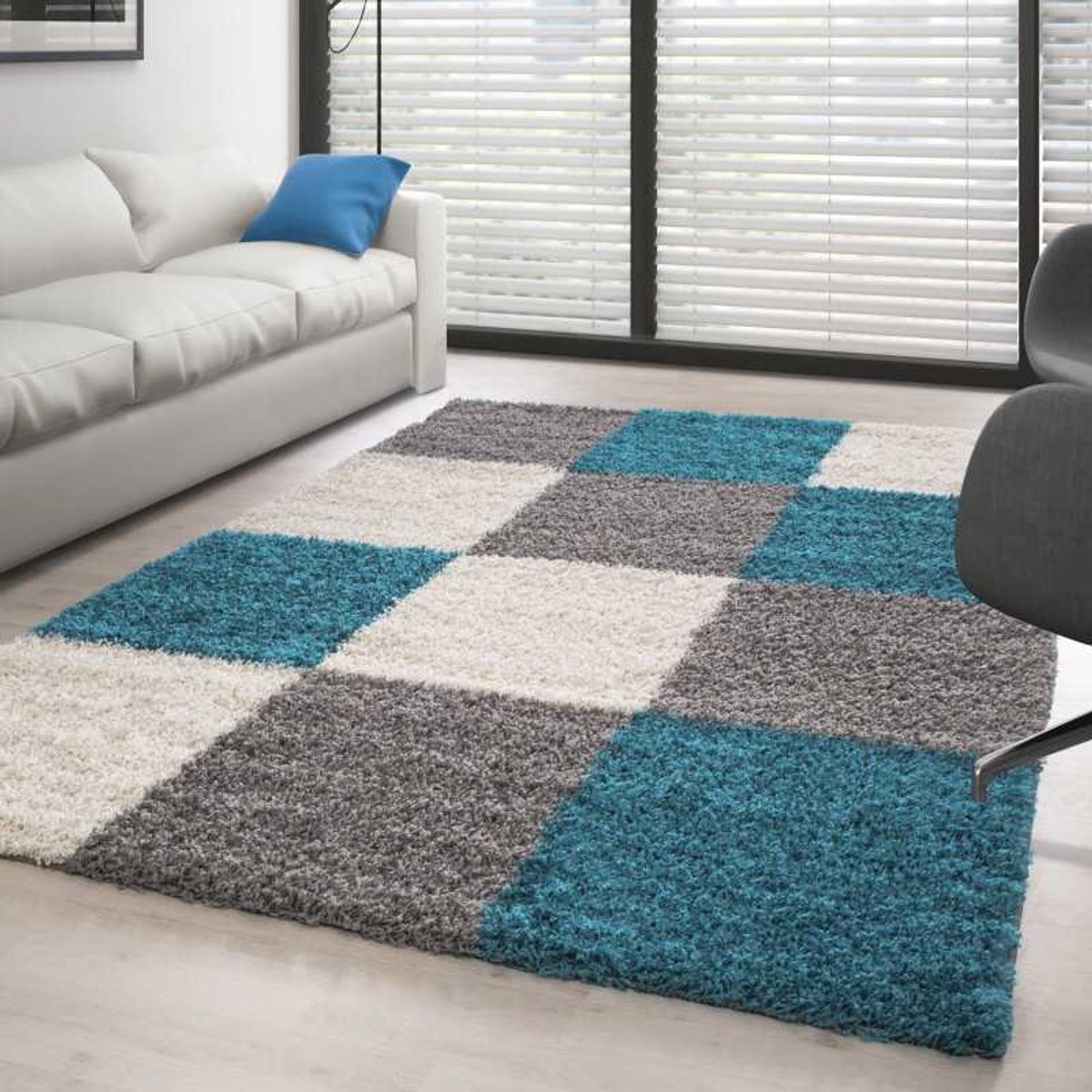 Hoogpolig vloerkleed met een turquoise-wit-grijs geblokt patroon. 60x110