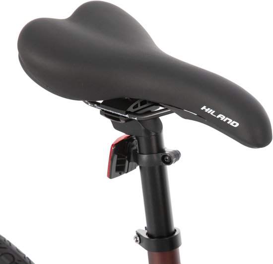 Zwart Hiland fietszadel met reflecterende tekst, gemonteerd op een zwarte zadelpen met rode reflector.