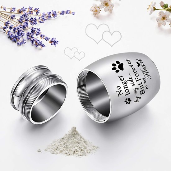 Zilverkleurige mini-urn van roestvrij staal, met open schroefdop en een hoopje as. Tekst: 'No longer by my side... But Forever in my Heart'.