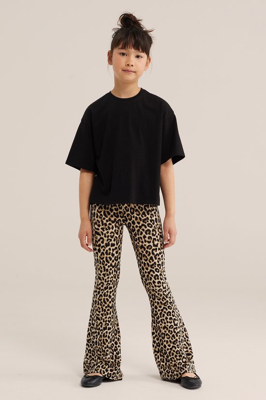 Jong meisje met opgestoken haar draagt een zwart oversized T-shirt en een broek met luipaardprint.