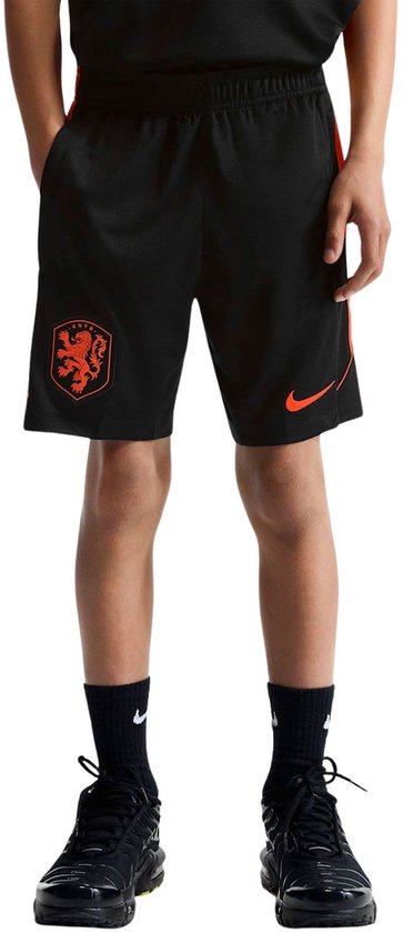 Zwarte Nike voetbalbroek met oranje logo links en oranje streep rechts, gedragen door een jongen.