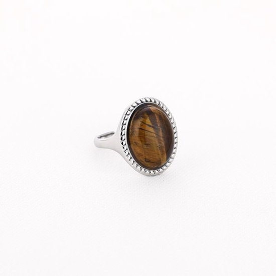 Zilverkleurige ring met een grote, ovale tijgeroog edelsteen met bruine strepen. De rand van de steen is versierd met een gedetailleerd patroon.