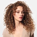 Portret van een vrouw met lang, golvend, bruin haar, met een beige top.