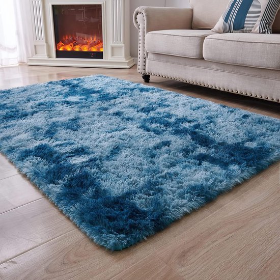 Un tapis moelleux à poils longs marbré bleu foncé et bleu clair sur un parquet, à côté d'un canapé et d'une cheminée.