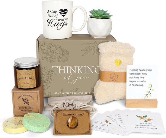 Boîte cadeau contenant une tasse, une bougie, des chaussettes douces, une pierre de confort, des produits de bain et des cartes de deuil.