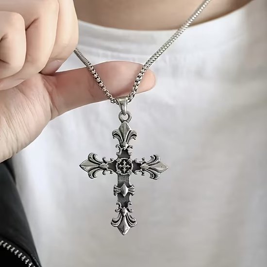 Zilverkleurige kruishanger met fleur-de-lis versieringen, gedragen aan een ketting.