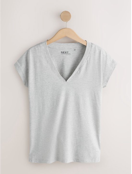 Lichtgrijs T-shirt met V-hals en korte mouwen, hangend aan een kapstok.