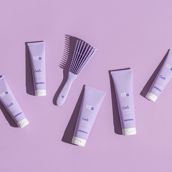 Paarse KIS Curls producten en borstel verspreid op paarse achtergrond.