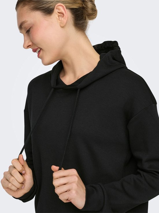 Model draagt een zwarte cropped hoodie.