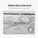Close-up van de grijze badmat die water absorbeert.