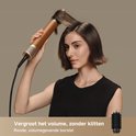 Une femme aux cheveux bruns courts se coiffe avec l'appareil doré et marron et une brosse ronde volumisante pour plus de volume.