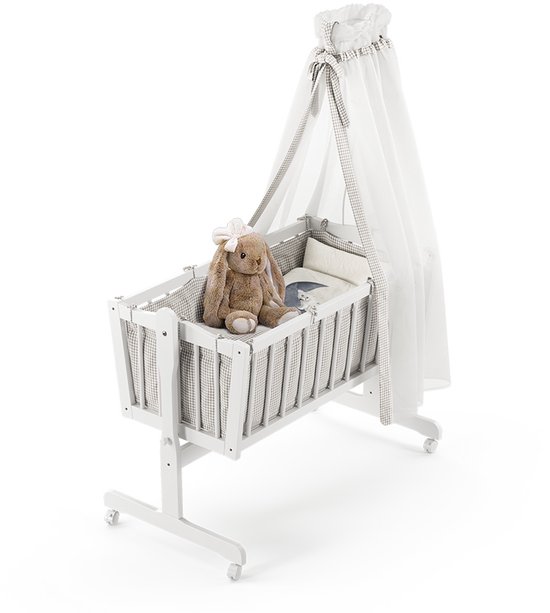 Wit kinderbed met hemel, ruitjespatroon, en teddybeer.
