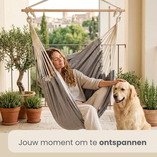 Grijze hangstoel met een vrouw en een hond op een balkon.