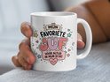 Witte mok met de tekst "MIJN FAVORIETE JUF VOOR ALTIJD IN MIJN HORT" in kleurrijke letters, versierd met hartjes en sterren.