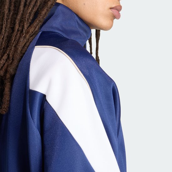 Close-up van een donkerblauwe sportjack met witte mouwaccenten en een beige bies.