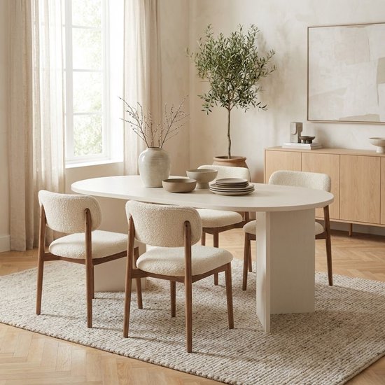 Ovale witte eettafel met vier stoelen in een lichte eetkamer.