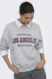 Model met grijze sweater met "LOS ANGELES WESTCOAST" print, gedragen over een wit overhemd.