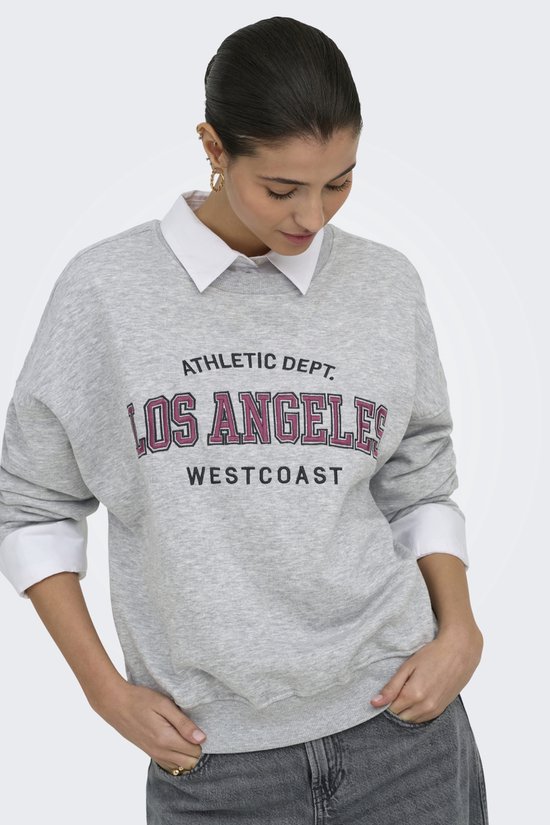 Model met grijze sweater met "LOS ANGELES WESTCOAST" print, gedragen over een wit overhemd.