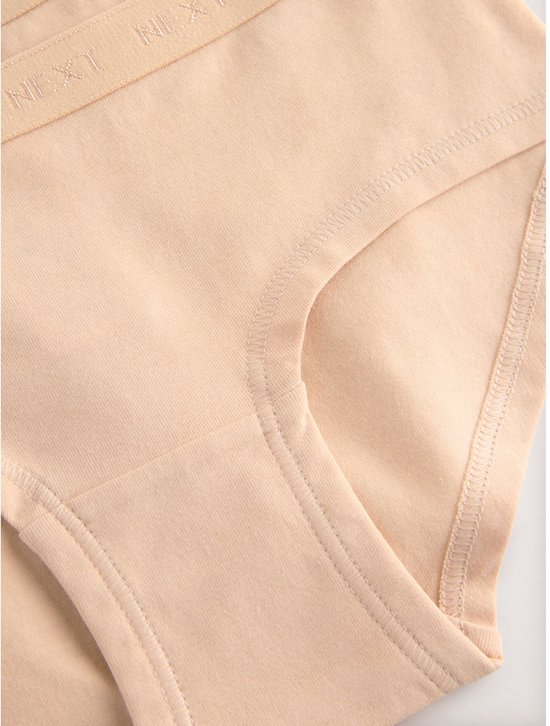 Close-up van de beenopening en tailleband van een beige hipster met NEXT-logo.