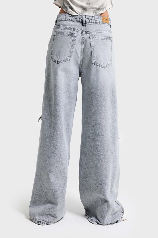 Achterkant van lichtgrijze baggy jeans met ritsdetails.