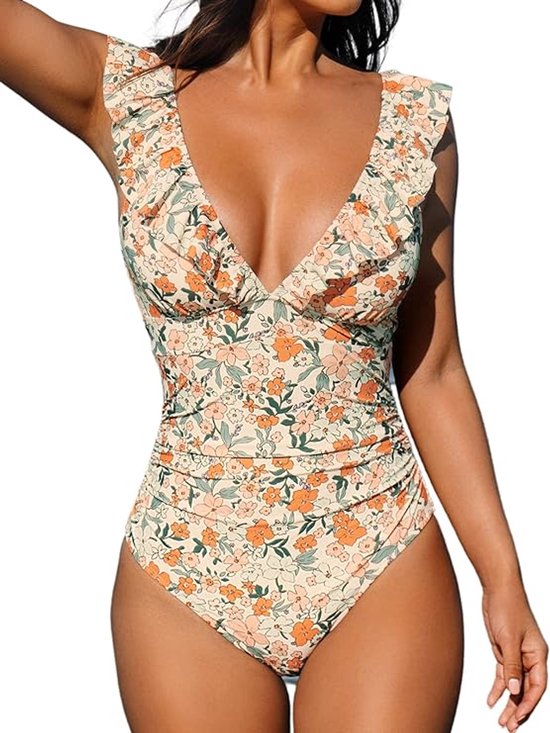 Model in badpak met bloemenprint in crème, oranje en groen. Met ruches aan de halslijn en diepe V-hals.