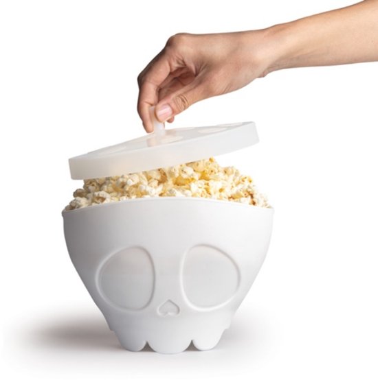 Witte schedel-vormige kom met popcorn, de deksel wordt geplaatst.