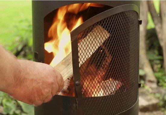 Hand legt houtblokken in brandende BonFeu tuinhaard met gaasdeur.