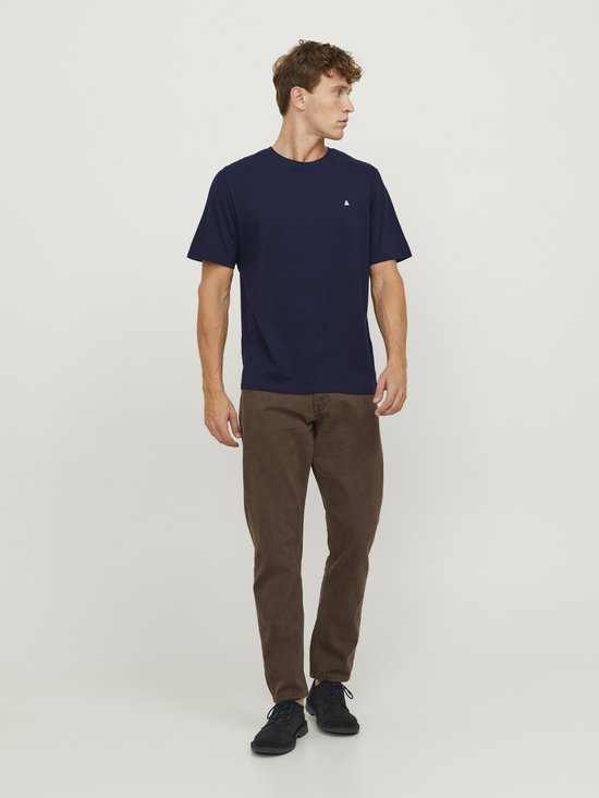 Homme portant un t-shirt bleu marine à manches courtes avec un '&' blanc sur la poitrine, associé à un pantalon marron.