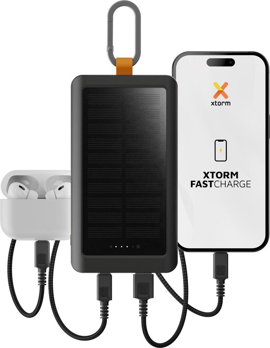 Zwarte Xtorm powerbank met zonnepaneel laadt een smartphone en oordopjes op.
