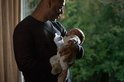 Een man houdt een slapende baby vast en geeft de baby een Philips Avent fles.
