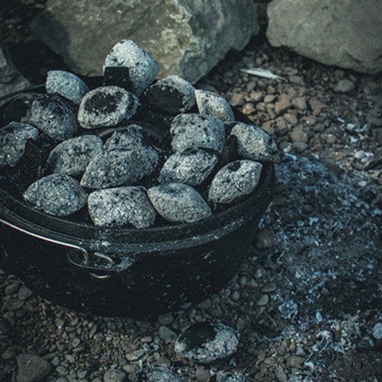 Zwarte gietijzeren Dutch oven, gevuld met gloeiende kolen.