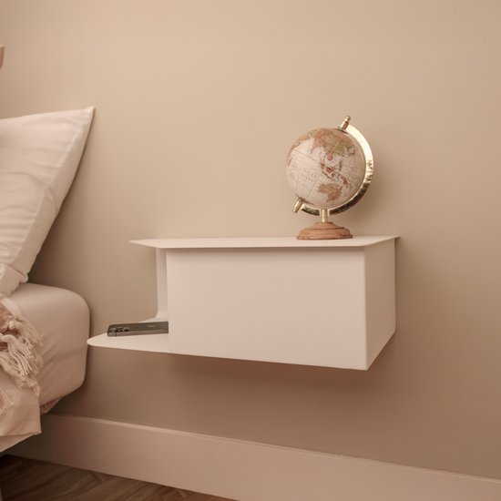 Wit nachtkastje met een globe en een telefoon erin, naast een bed.