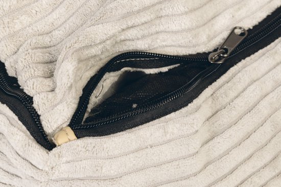 Close-up van een open rits met een beige insteek op een lichte crèmekleurige ribstof hondenmand.