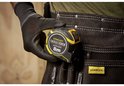Hand met zwarte handschoen houdt gele en zwarte Stanley FatMax 8m rolbandmaat vast.