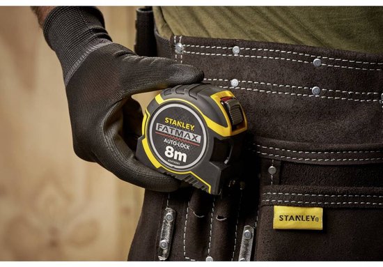 Hand met zwarte handschoen houdt gele en zwarte Stanley FatMax 8m rolbandmaat vast.