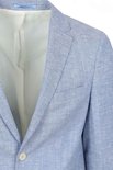 Close-up van een lichtblauwe linnen blazer met één knoop, borstzak en lichte textuur.