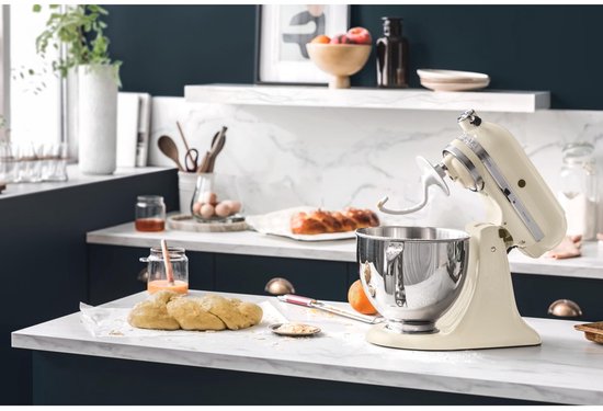 Licht beige KitchenAid Artisan mixer in een keuken met deeg en fruit.