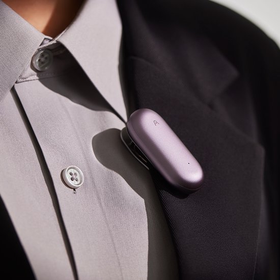 Paars PLAUD NotePin-apparaat met clip op de revers van een pak.