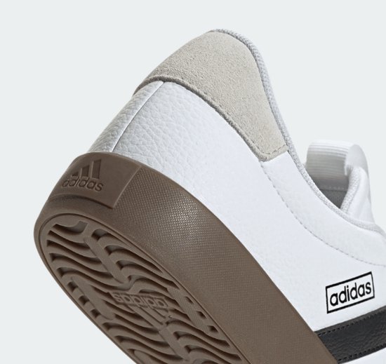 Achterkant van een witte sneaker met bruine zool en beige hielstuk. Adidas logo op de zool.