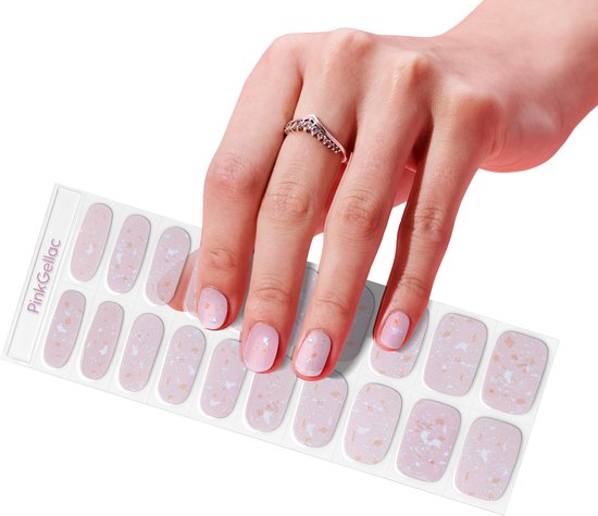 Hand met nagels aangebracht met roze, holografische terrazzo nagelstickers. Een ring met v-vormige zirkonia's is zichtbaar.