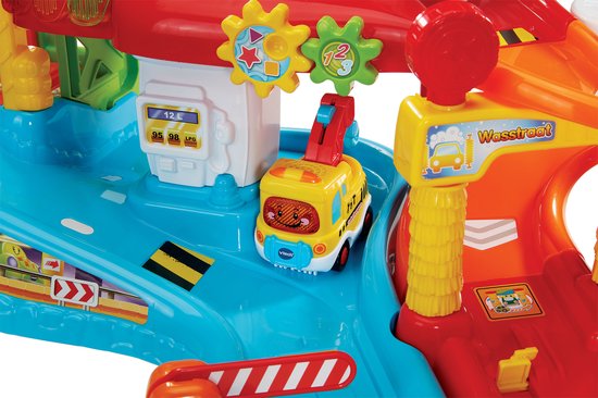 Gedetailleerde close-up van de VTech Toet Toet Auto's speelgoedgarage: auto's bij de pomp en wasstraat.
