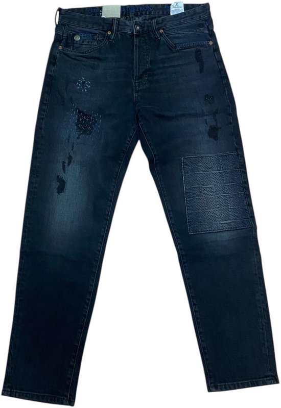 Donkere Cast Iron spijkerbroek met een relaxed pasvorm, distressed details, patches en een zichtbare leren label aan de tailleband.