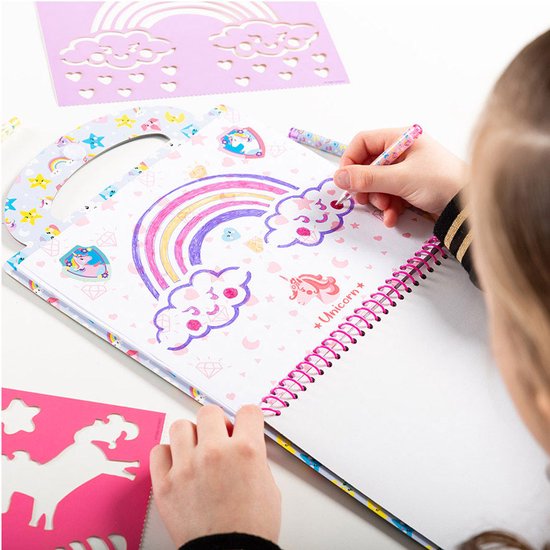 Une fille avec un détail imprimé léopard sur sa veste dessine un arc-en-ciel avec des nuages dans un livre d'activités Licorne.