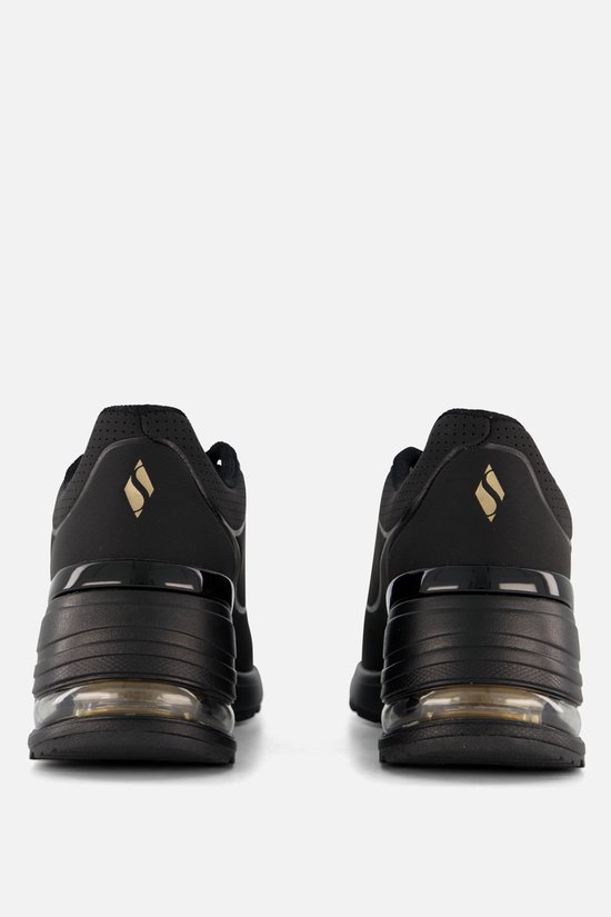 Achterkant van een paar zwarte Skechers sneakers, met gouden logo.