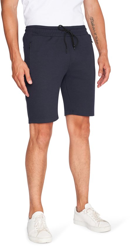 Man die een donkerblauwe korte broek met trekkoord en ritssluitingen aan de zijkant draagt.