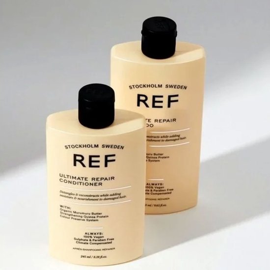 Twee lichtgele flessen REF Stockholm Ultimate Repair. De fles op de voorgrond is een conditioner, de fles op de achtergrond een shampoo.