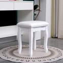 Witte kaptafelkruk met gebogen poten, gestoffeerd zitvlak, naast een witte kaptafel.